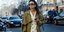 Γυναίκα στους δρόμους της πόλης με ριγέ πανωφόρι, μπεζ σύνολο και γυαλιά ηλίου