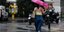 Μια γυναίκα περπατά στην Αθήνα κατά τη διάρκεια καλοκαιρινής βροχής