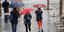 Τρεις γυναίκες περπατούν σε παλαιότερη καλοκαιρινή βροχή, κρατώντας ομπρέλες