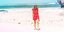 Γυναίκα με κόκκινα ρούχα περπατάει στην παραλία 