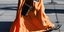 Γυναίκα με μακρύ, πορτοκαλί φόρεμα και μπότες