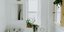 Λευκό μπάνιο με πλακάκια με γεωμετρικά μοτίβα, φυτά, καθρέπτη, παράθυρο