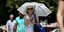 Γυναίκα με ομπρέλα θέλει να προστατευτεί από τον ζεστό καιρό και τον ήλιο