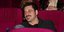 Ο Γιώργος Χρυσοστόμου κάθεται στο θέατρο και φοράει τζιν και μαύρο πουκάμισο