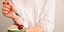 Γυναίκα με κόκκινα νύχια κρατάει μπολ με γιαούρτι και κεράσια