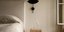 Κρεβατοκάμαρα διαμερίσματος με ξύλινο κομοδίνο, κρεβάτι, λευκό παράθυρο, μαύρο διακοσμητικό στον τοίχο