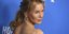 Η Ρενέ Ζελβέγκερ με πιασμένα τα μαλλιά και μπλε φόντο 
