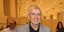 Ο Ερρίκος Πετιλόν με γκρι σακάκι χαμογελά στον φωτογραφικό φακό