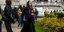 Γυναίκα με μωβ πουλόβερ, μαύρη κάπα και μαύρο παντελόνι στην Εβδομάδα Μόδας
