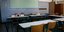 Σχολική αίθουσα ελληνικού σχολείου με θρανία σε σχήμα Π και πράσινο πίνακα