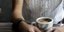 Γυναικεία χέρια με τατουάζ στο μπράτσο κρατούν μια κούπα καφέ