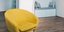 Μια κίτρινη πολυθρόνα σε σαλόνι με ξύλινο πάτωμα