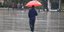 Ανδρας κρατάει ομπρέλα στη βροχή