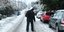 Ανδρας περπατά σε χιονισμένο δρόμο