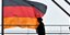 Ανθρωποι περνούν μπροστά από τη σημαία της Γερμανίας