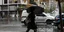 Γυναίκα με μαύρα ρούχα και ομπρέλα περπατάει