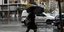 Γυναίκα με μαύρα ρούχα και ομπρέλα περπατάει