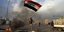 Άνδρας παιανίζει σημαία σε βομβαρδισμένο σημείο στο Ιράκ