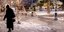Γυναίκα περπατά σε χιονισμένη πλατεία στην Αθήνα