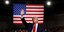 Ο Ντόναλντ Τραμπ χαιρετάει το κοινό μπροστά από σημαία των ΗΠΑ