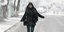 Κοπέλα περπατά σε χιονισμένο δρόμο