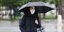 Γυναίκα με μάσκα, ομπρέλα και μπουφάν