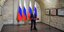 O Βλάντιμιρ Πούτιν μιλάει σε μικρόφωνο μπροστά από ρωσικές σημαίες