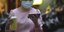 Γυναίκα με ροζ μπλούζα και μάσκα, κρατά το κινητό της στο χέρι