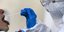 Γιατρός με στολή, μάσκα και γάντια πραγματοποιεί τεστ για τον κορωνοϊό με τη μέθοδο του επιχρίσματος
