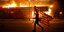 Διαδηλωτής με αστερόεσσα μπροστά σε φλεγόμενο κτίριο στη Μινεάπολις