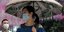 Γυναίκα με ομπρέλα και μάσκα για τον κορωνοϊό στην Κίνα