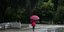 Γυναίκα με ροζ ομπρέλα περπατά στην βροχή