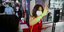 Κινέζα με κόκκινο φόρεμα και κινητό σηκώνει το χέρι της