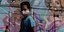 Νεαρός με μάσκα για τον κορωνοϊό περπατά μπροστά από γκράφιτι στην Βραζιλία