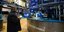 Χρηματιστής στη Νέα Υόρκη κρατά τάμπλετ μπροστά από οθόνες