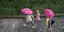Γυναίκα με τα παιδιά της κρατούν ροζ ομπρέλες