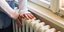 Επίδομα θέρμανσης: Μια γυναίκα ακουμπά τα χέρια της σε καλοριφέρ για να ζεσταθεί