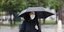 Γυναίκα με μαύρη ομπρέλα και μάσκα
