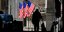 Ανθρωπος περπατά σε σκιά μπροστά από τις σημαίες στο χρηματιστήριο της Γουόλ Στριτ
