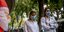 Νοσηλεύτριες με μάσκα περνούν μπροστά από φουσκωτό Αϊ-Βασίλη