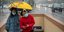 Κινέζοι με μάσκες και ομπρέλα κάτω από βροχή