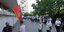 Πολίτες με αποστάσεις αναμένουν στην ουρά μπροστά από ένα κτίριο με τη σημαία του Μαυροβουνίου