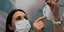 Νοσοκόμα με μάσκα κρατά σύριγγα με το εμβόλιο για τον κορωνοϊό