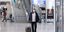 Ταξιδιώτης με μάσκα και βαλίτσα στο αεροδρόμιο