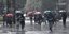 Πολίτες περπατούν με ομπρέλες κάτω από βροχή