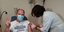 Άνδρας κάνει το σήμα της νίκης στο νοσοκομείο Κέρκυρας, ενώ κάνει την πρώτη δόση του εμβολίου για τον κορωνοϊό