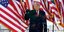 Ο Ντόναλντ Τραμπ μπροστά από αμερικανικές σημαίες υψώνει τη γροθιά του