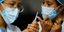 Νοσοκόμες κρατούν σύριγγα με το εμβόλιο της AstraZeneca