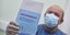 Πολίτης με μάσκα κρατά το πιστοποιητικό για το ρωσικό εμβόλιο