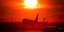 Αεροπλάνο προσγειώνεται σε αεροδιάδρομο την ώρα που δύει ο ήλιος